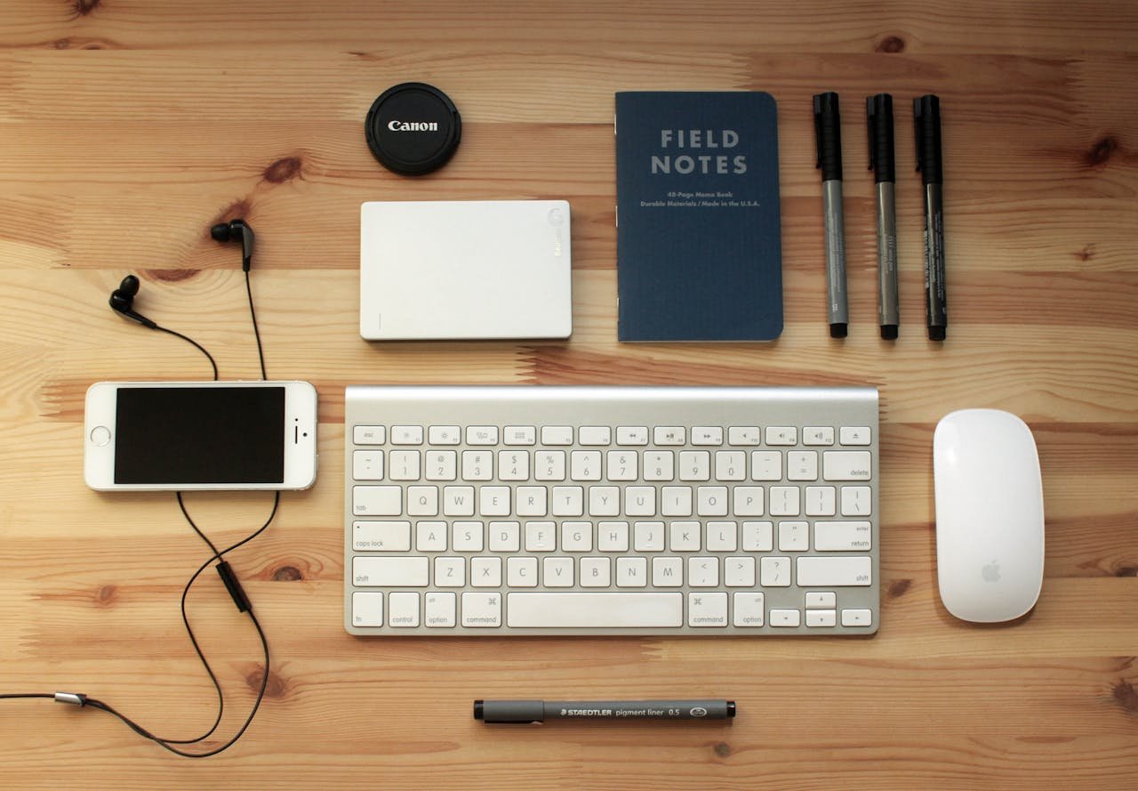 services-03 Top view of a modern desk setup featuring electronics, stationery, and gadgets on a wooden surface.